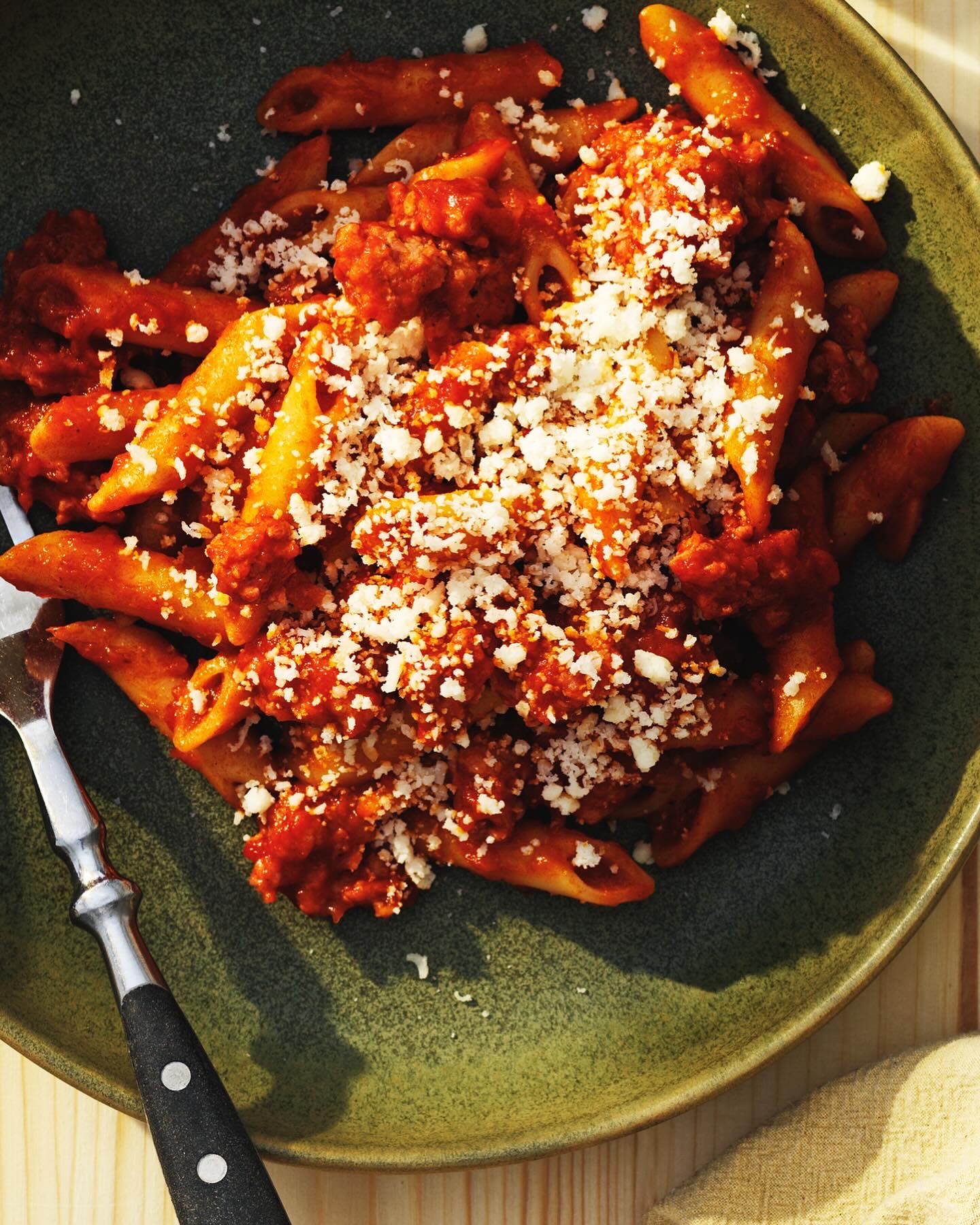 Penne i tomatsås med riven ost i grön skål